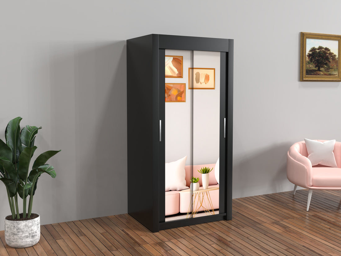 Black wardrobe with sliding doors in a room with a pink sofa and plant.