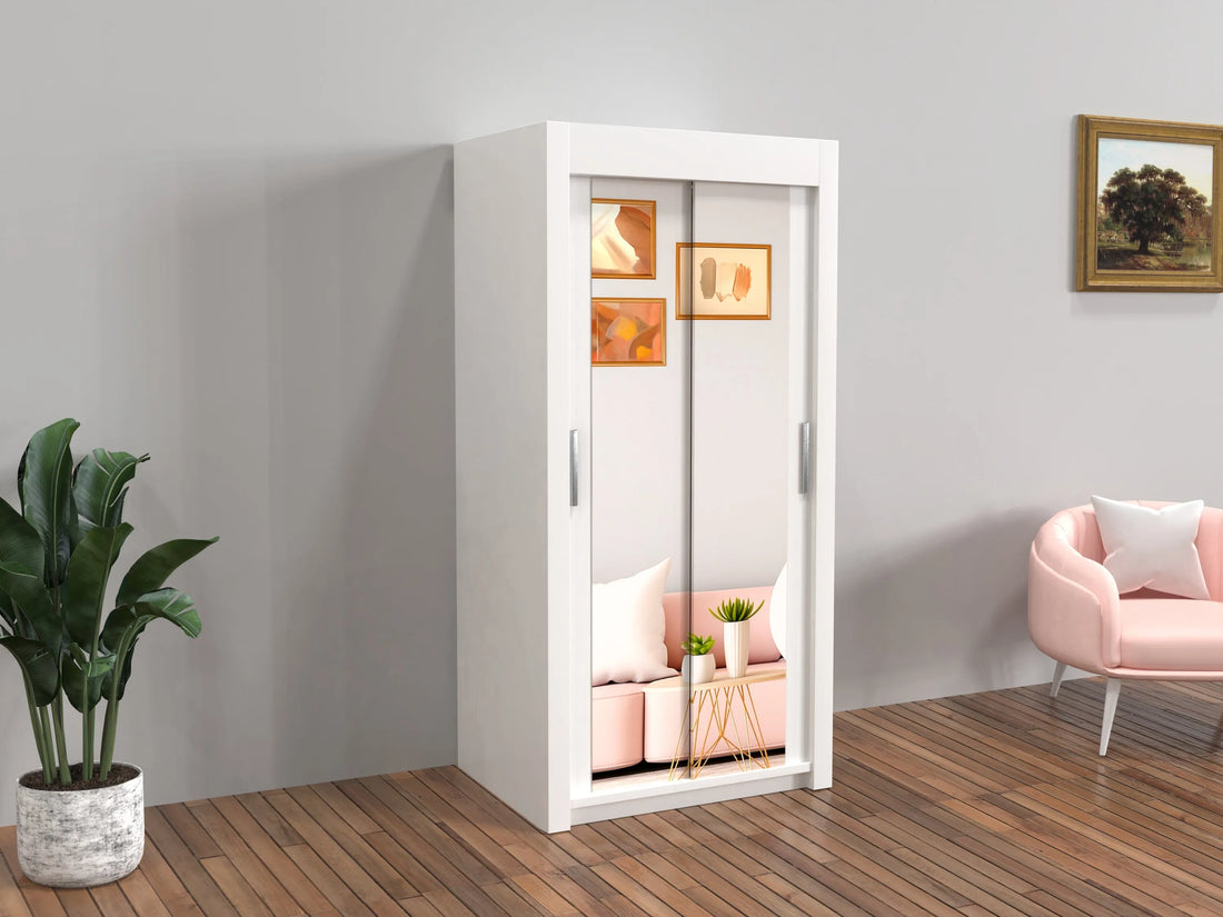 White wardrobe with sliding doors in a room with a pink chair and plant.