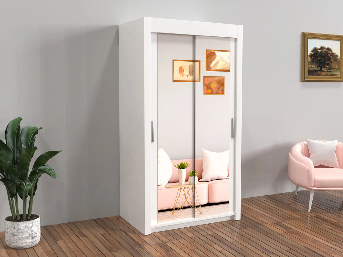 White wardrobe with sliding glass doors in a room with a pink chair and plant.